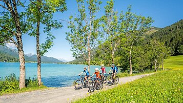 Familie beim Fahrradfahren am See in Kärnten.