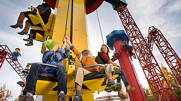 Kinder sitzen im Legoland Bayern in einem Fahrgeschäft.