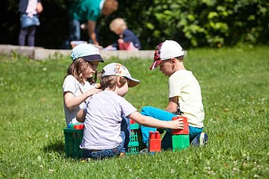 m Familienhotel der Ponyhof Steiermark spielen Kleinkinder auf der Wiesen mit Bausteinen.