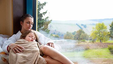 Mutter und Tochter liegen im Bademantel gemeinsam im Wellnessbereich des Elldus Resorts im Erzgebirge.