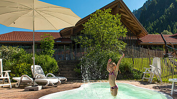Kind planscht im Outdoor-Pool für Kinder des Spa- & Familien-Resorts Krone im sommerlichen Allgäu.