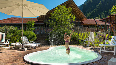 Kind planscht im Outdoor-Pool für Kinder des Spa- & Familien-Resorts Krone im sommerlichen Allgäu.