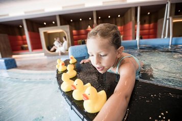 Kind spielt mit Badeenten im Kinderpool des Familienhotels Allgäuer Berghof.
