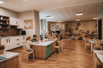 Im Kidsclub des Familienhotel Mia Alpina in Tirol spielen Kinder an kleinen Tischen in einem hellen Happy-Club.