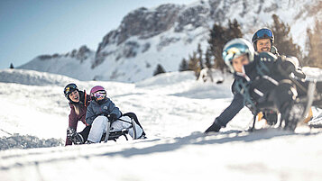 Kinder beim Schlitten fahren in Südtirol. Der Winter eignet sich für jeden Familienurlaub in der Region.