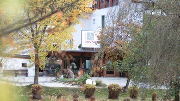 Hotelansicht im herbst des Alpenhof Dolomit Family in Südtirol, Ententeich und herbstlich gefärbte Bäume vor dem Familienhotel