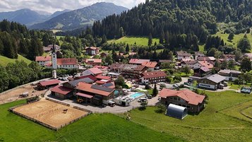 Luftaufnahme des Familienhotels Krone im Allgäu mit Blick auf Reitplatz, Pool und umliegende Natur.