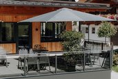 Sonnenterrasse des Familienhotels Oberkarteis mit modernen Sitzplätzen, Sonnenschirmen und gemütlicher Atmosphäre im Sommer.