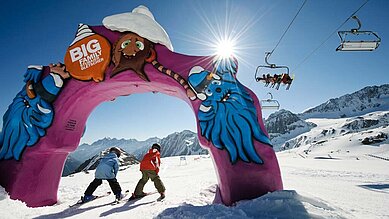 Zwei Kinder fahren auf Skiern durch einen Bogen, der sich im familienfreundlichen Skigebiet nahe des Alpenhotels Kindl.