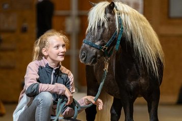 Das Mädchen freut sich das Pony im Elldus Resort Im Erzgebirge auszuführen.