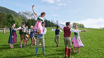 Salzburger Land Ausflugstipps: Bauerherbst mit tanzenden jungen Leuten in Tracht auf einer grünen Wiese