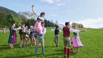 Salzburger Land Ausflugstipps: Bauerherbst mit tanzenden jungen Leuten in Tracht auf einer grünen Wiese