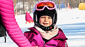 Mädchen in Skiausrüstung auf der Skipiste im Bayerischen Wald.