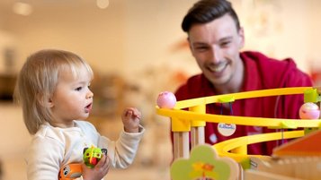 Kinderbetreuer spielt mit einem Kleinkind im Happy-Club des Familienhotels Sonnenpark.