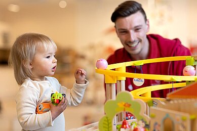 Kinderbetreuer spielt mit einem Kleinkind im Happy-Club des Familienhotels Sonnenpark.