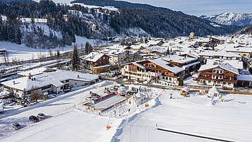 Luftaufnahme im Winter vom Familienhotel das Hopfgarten mit Ausblick auf die Landschaft.