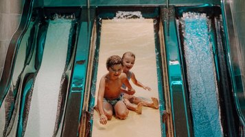 Zwei Kinder haben fröhlichen Rutschenspaß im Familienhotel Oberkarteis und genießen das Wasserabenteuer.