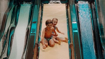 Zwei Kinder haben fröhlichen Rutschenspaß im Familienhotel Oberkarteis und genießen das Wasserabenteuer.
