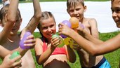 Kinder mit Wasserbomben beim Sommerspaß im Garten des Familienhotels Ramsi