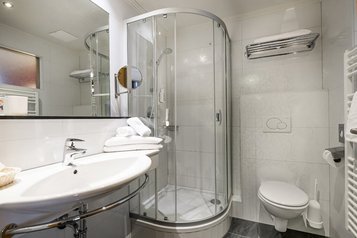 Modern ausgestattetes Badezimmer im Familienhotel Zauchenseehof im Salzburger Land mit Dusche, WC und großzügigem Waschbereich.