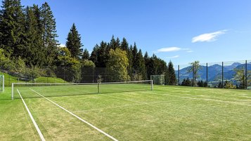 Blick über den neuen Tennisplatz mit Kunstrasen am Familienhotel Allgäuer Berghof und den Allgäuer Bergen im Hintergrund.