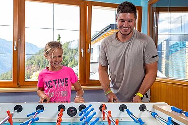 Vater spielt mit seinem Kind am Tischkicker im Adler Familien- & Wohlfühlhotel in Tirol.