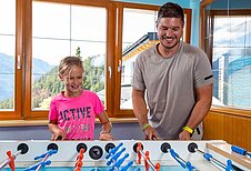 Vater spielt mit seinem Kind am Tischkicker im Adler Familien- & Wohlfühlhotel in Tirol.