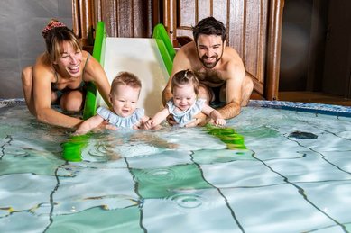Eine junge Familie genießt gemeinsam das Plantschvergnügen im Babybecken des Familienhotels Das Bayrischzell in Oberbayern