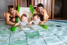 Eine junge Familie genießt gemeinsam das Plantschvergnügen im Babybecken des Familienhotels Das Bayrischzell in Oberbayern