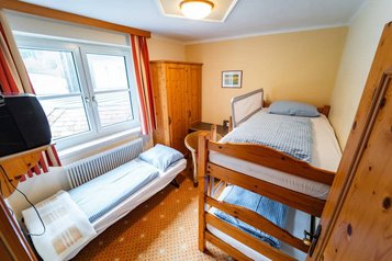 Gemütliches Kinderzimmer im Familienhotel Bruckwirt mit Etagenbett, Einzelbett und rustikaler Holzeinrichtung.