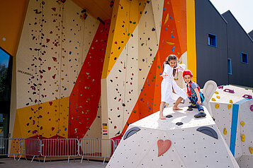 Kinder stehen auf einem Kletterfelsen im Indoor Funpark im Familienhotel Kolping Hotel Spa & Family Resort in Ungarn.