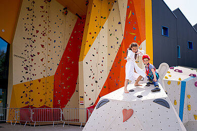 Kinder stehen auf einem Kletterfelsen im Indoor Funpark im Familienhotel Kolping Hotel Spa & Family Resort in Ungarn.
