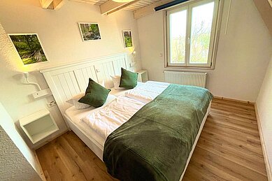 Gemütlich eingerichtete Premium Suite im Family Club Harz, mit einem Doppelbett, Babybett und einem Sofa.