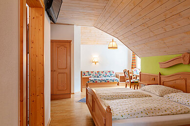 Familienzimmer mit Doppelbett und Sitzbank im Kinderhotel Bruckwirt in Oberösterreich.