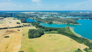 Ein See mit einem Dorf und Wald außen rum.