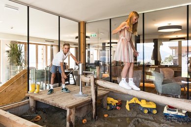 Zwei Kinder spielen in dem Indoor-Sandspielplatz im Almfamilyhotel Scherer in Tirol