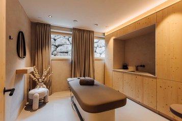 Moderner Behandlungsraum mit Massageliege im Familienhotel Post Family Resort.