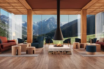 Helle Lounge mit Sitzbereichen, Kamin und grossen Fenstern mit Bergblick im Familienhotel Bella Vista in Suedtirol.