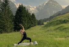 Yoga inmitten einer alpinen Wiesenlandschaft mit Bergpanorama nahe dem Familienhotel Bella Vista in Südtirol.