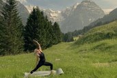 Yoga inmitten einer alpinen Wiesenlandschaft mit Bergpanorama nahe dem Familienhotel Bella Vista in Südtirol.