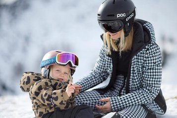 Eine Mutter mit ihrer Tochter im Skianzug im Schnee in der Nähe des Familienhotels Das Bayrischzell in Oberbayern.