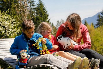 Kinder streicheln ein Kaninchen auf der Sonnenliege beim Familienhotel Ramsi