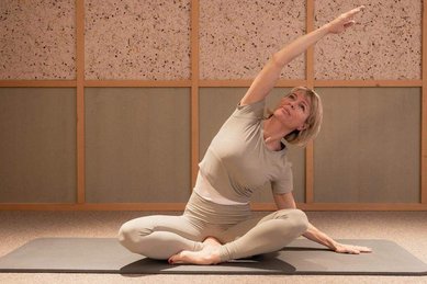 Eine Frau macht Yoga und Dehnuebungen in einem ruhigen Entspannungsbereich im Hotel Bella Vista in Südtirol.