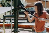 Ein Kind spielt am Wasserspielplatz mit einer Pumpe im Außenbereich des Familienhotels Oberkarteis im Salzburger Land.