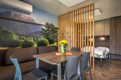 Moderner Wohnraum im Tiny House des Familienhotels Ramsi mit gemütlicher Sitzecke, Esstisch und Blick auf das Schlafzimmer