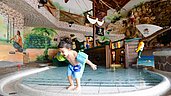 Kind planscht im Piraten-Kinderbecken und bewundert die Dekoration im Familienhotel Ulrichshof im Bayerischen Wald