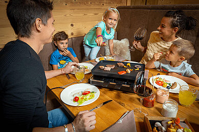 Familie genießt ihr privates Raclette zu Abend im Familienurlaub in den Mons Silva Private Luxury Chalets in Südtirol.