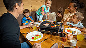Familie genießt ihr privates Raclette zu Abend im Familienurlaub in den Mons Silva Private Luxury Chalets in Südtirol.