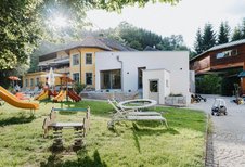 Der Spielplatz vor dem Kinderhotel Bruckwirt in Oberösterreich ist mit dem Hotelgebäude im Hintergrund zu sehen.