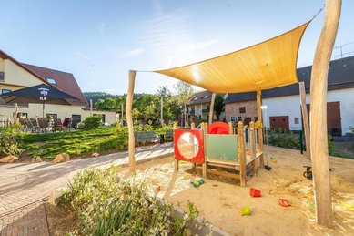 Sandspielplatz im Familienhotel Ottonenhof im Sauerland mit Sonnensegel, Spielgeräten und Sandspielzeug.